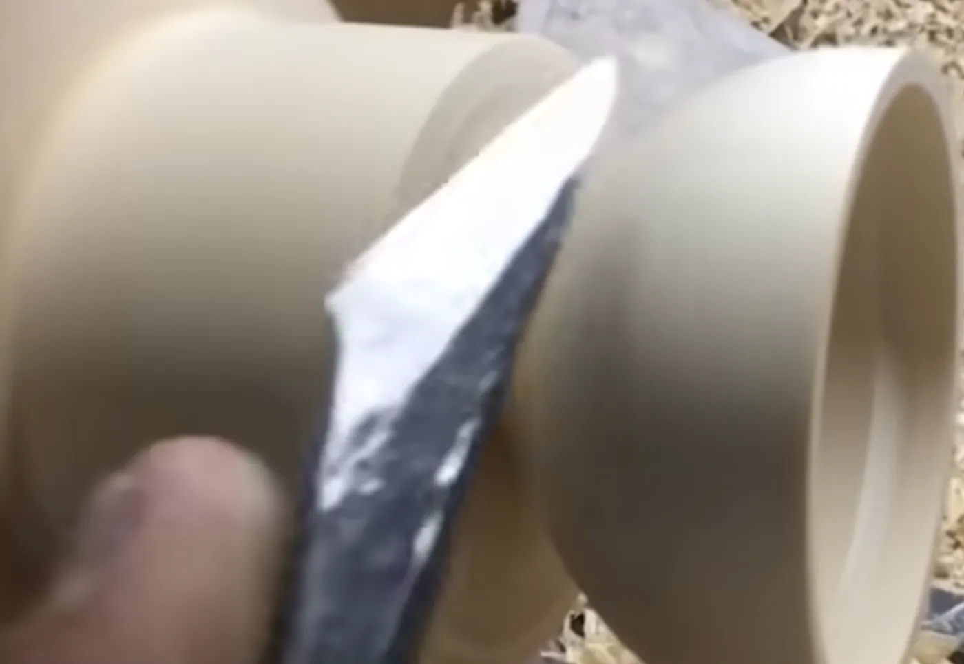 The lathe knife taking a clean pass along the rim of a turned bowl